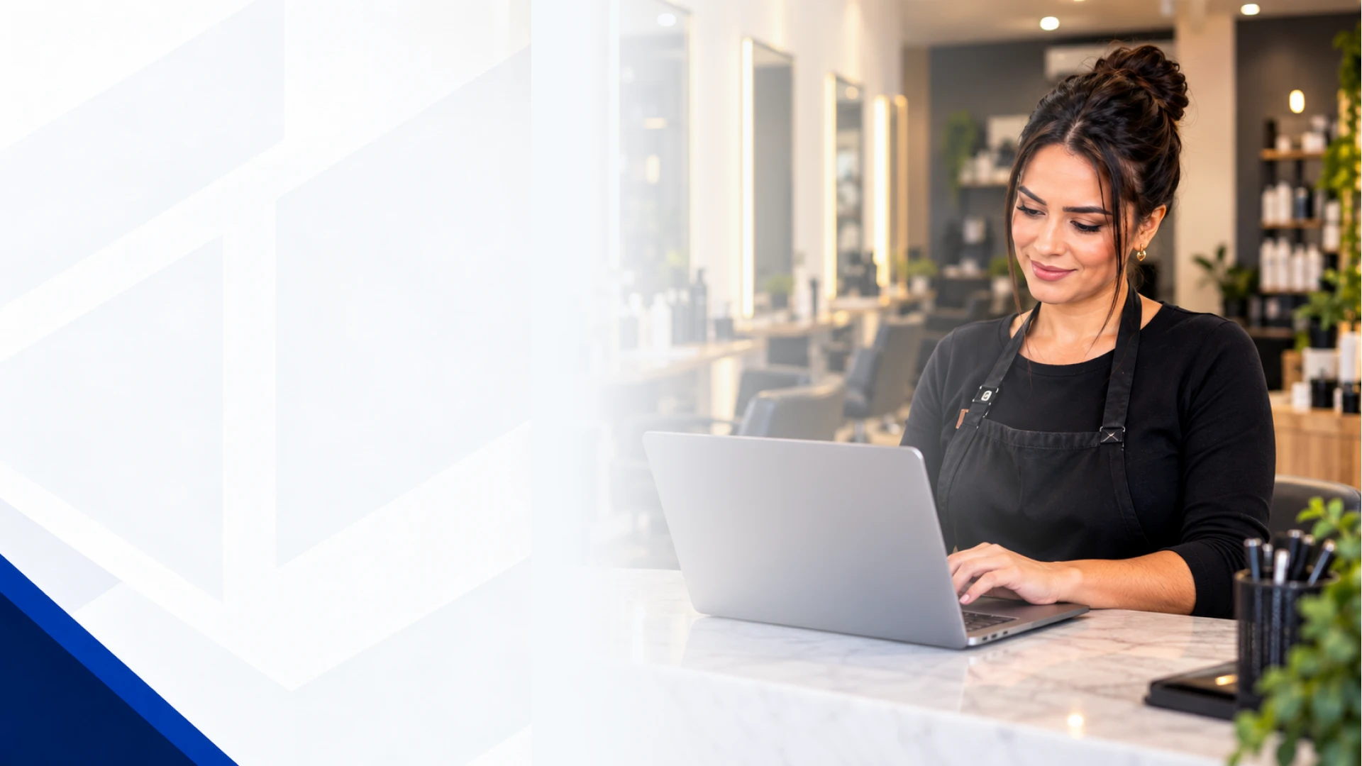 Dona de salão de beleza sorrindo enquanto trabalha no notebook, em um salão iluminado
